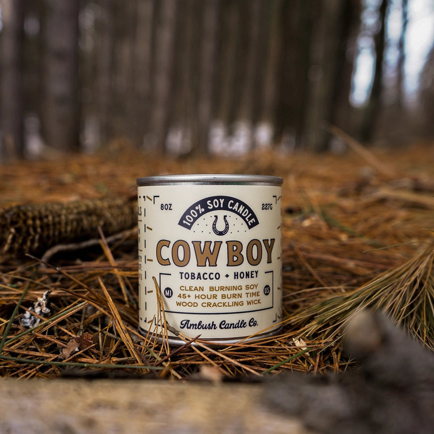 Cowboy brand candle can on a bed of pine needles with a forest background